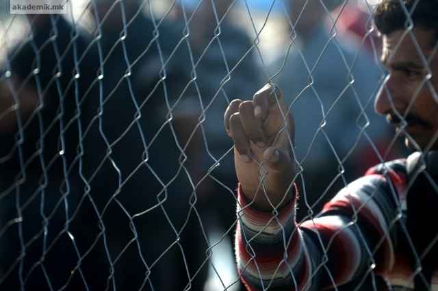 epa04942170 A migrant clutches to a fence as they are waiting for a permission to move towards the train station at a refugee camp near Gevgelija, The Former Yugoslav Republic of Macedonia, 21 September 2015. The main migration route across the Balkans - from Turkey, across Greece, Macedonia and Serbia - previously led to Hungary. But after Hungary sealed its borders, migrants began taking an alternative route to Western Europe via Croatia, the EU's newest member. EPA/NAKE BATEV